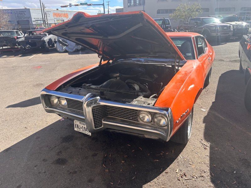 Orange classic car with hood open at an outdoor car show, showing its engine bay | Pro Veterans Automotive