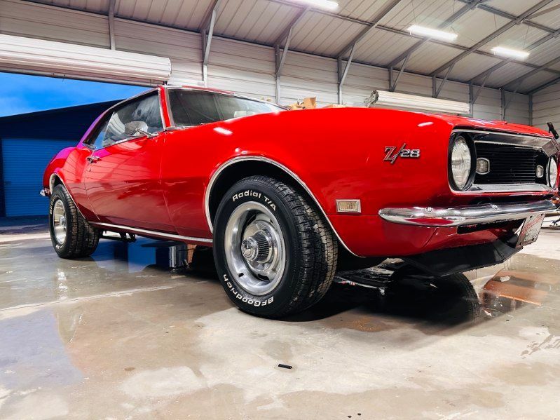 Red classic muscle car in a garage, viewed from the front-left side. | Pro Veterans Automotive
