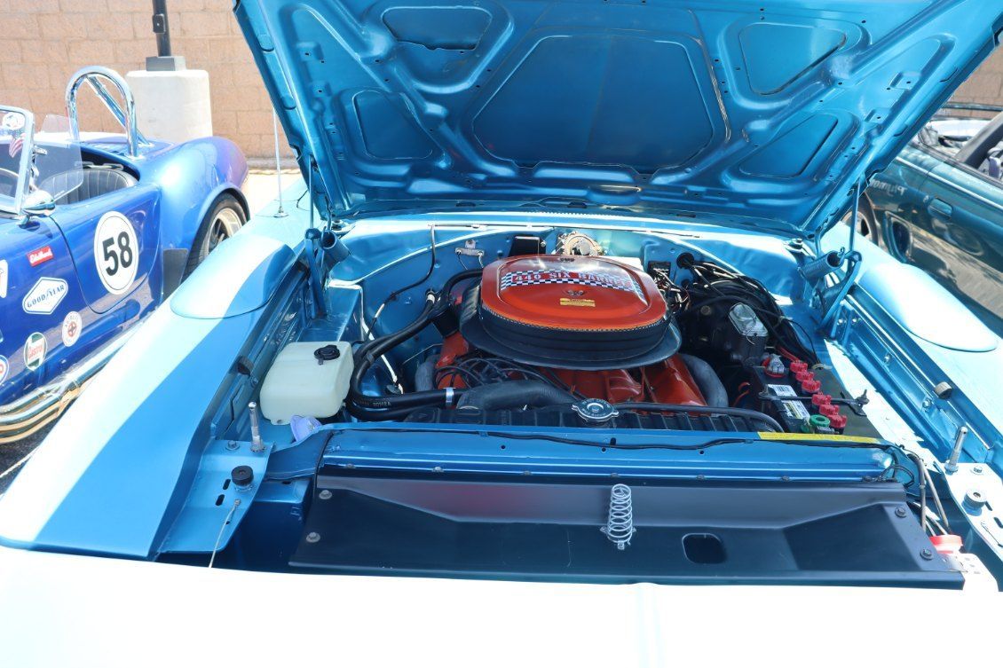 Open blue classic car hood revealing a red air filter and engine bay at a car show | Pro Veterans Automotive