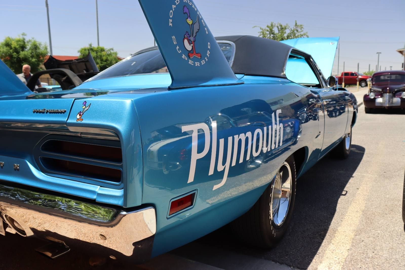 Blue Plymouth muscle car with hood scoop and raised rear wing at an outdoor car show | Pro Veterans Automotive