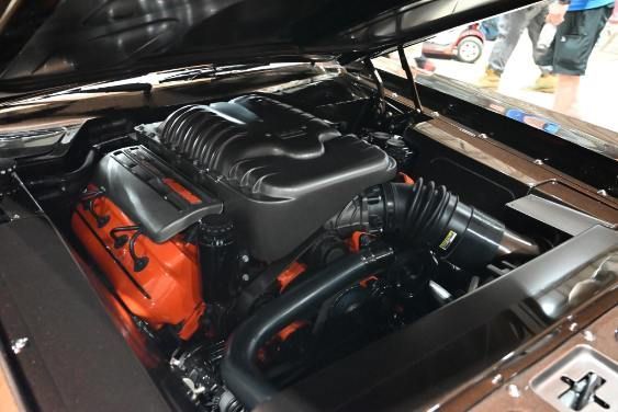 Close-up of a car engine bay with a black and orange engine cover under an open hood | Pro Veterans Automotive