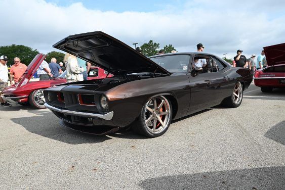 Black classic muscle car with hood open at a car show, people and other cars in the background | Pro Veterans Automotive