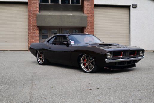 Black classic muscle car parked outside a building, angled front view | Pro Veterans Automotive