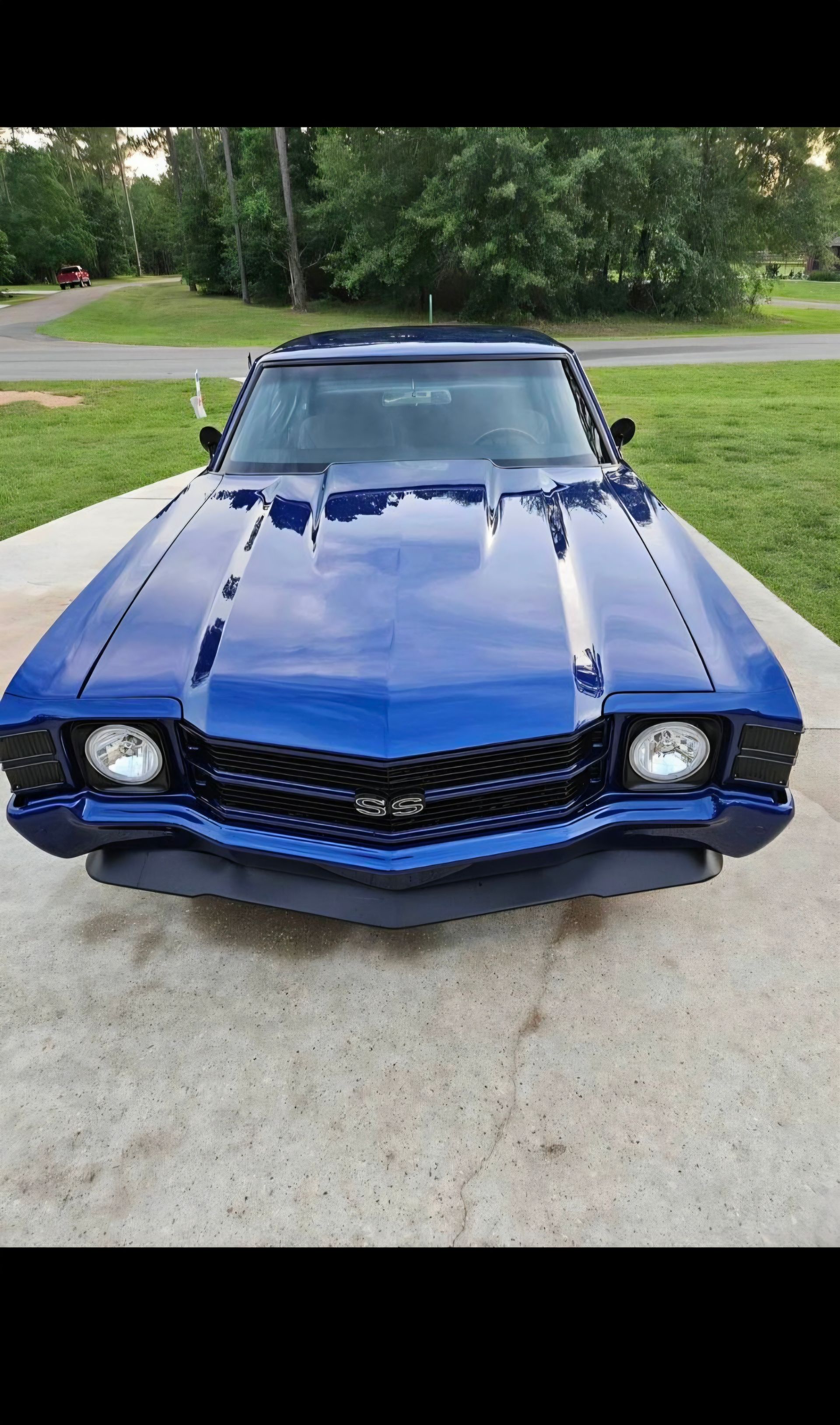 Blue classic car parked on a driveway with green lawn and trees in the background | Pro Veterans Automotive