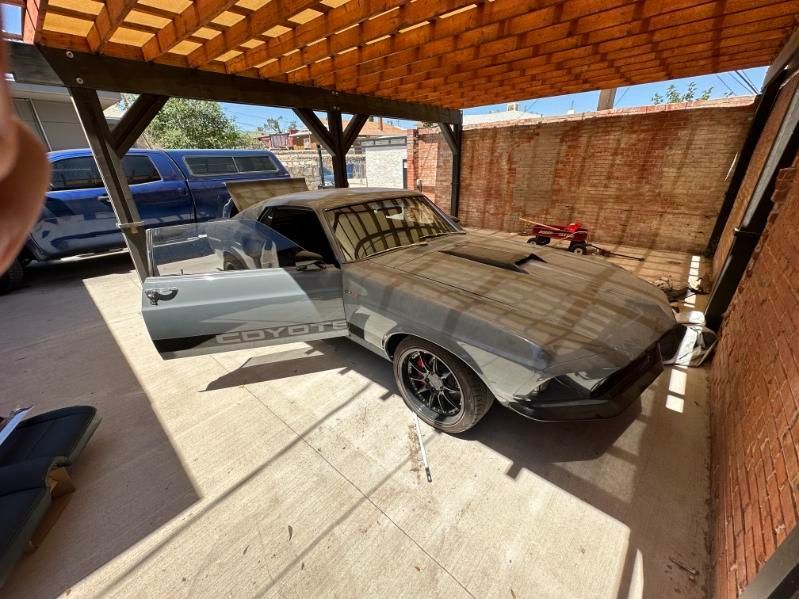 Matte gray classic car parked in a brick carport, with its driver door open. | Pro Veterans Automotive