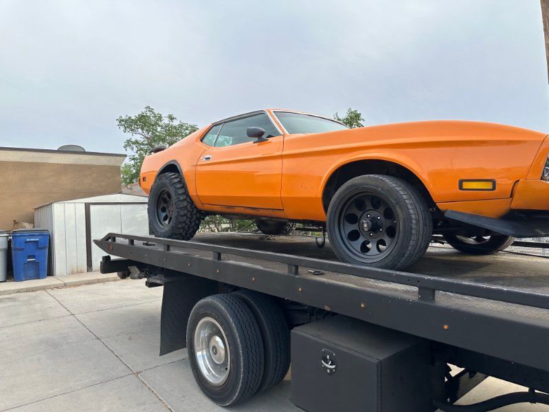 Orange classic car on a black flatbed tow truck in a driveway | Pro Veterans Automotive