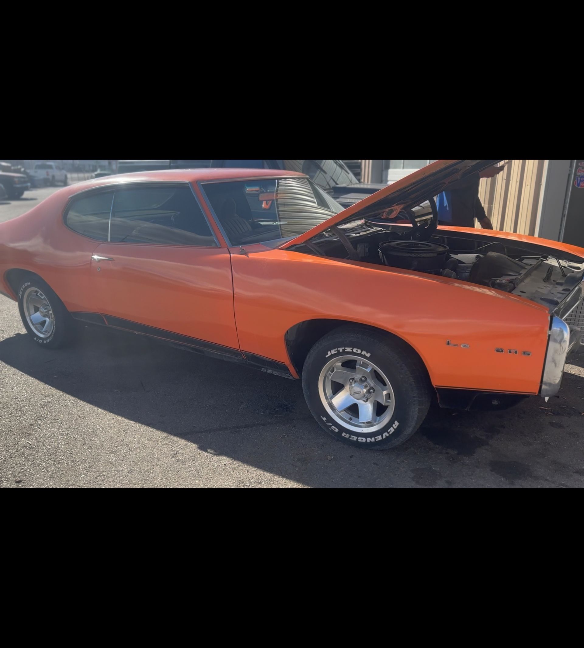 Orange classic muscle car with hood open, parked outdoors on gravel | Pro Veterans Automotive