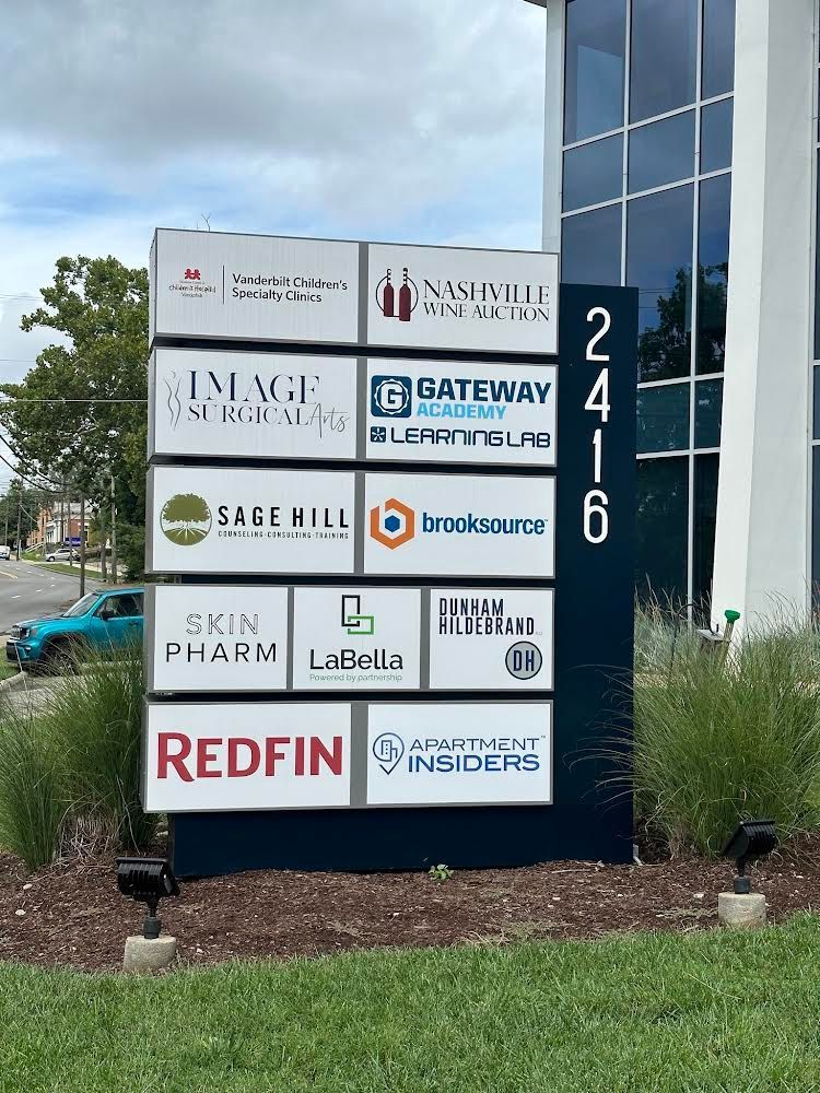 A large sign in front of a building with lots of logos on it.