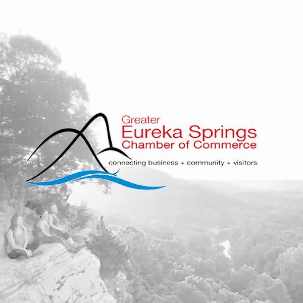 Logo for the Greater Eureka Springs Chamber of Commerce overlaid on a faint, black and white scenic nature landscape.