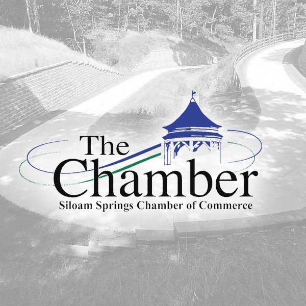 The logo for the Siloam Springs Chamber of Commerce, featuring a blue gazebo icon above the text on a blurred park background.