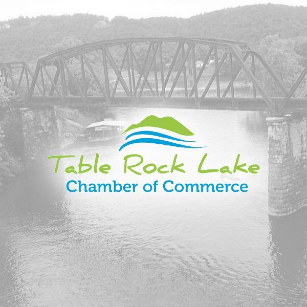 The Table Rock Lake Chamber of Commerce logo featuring a stylized green hill and blue water waves over a faded bridge.
