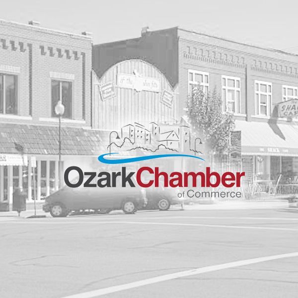 Logo for the Ozark Chamber of Commerce over a faded, grayscale street-level view of a downtown building facade.