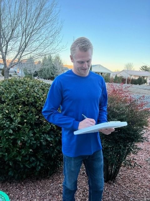 A man in a blue shirt is writing on a clipboard