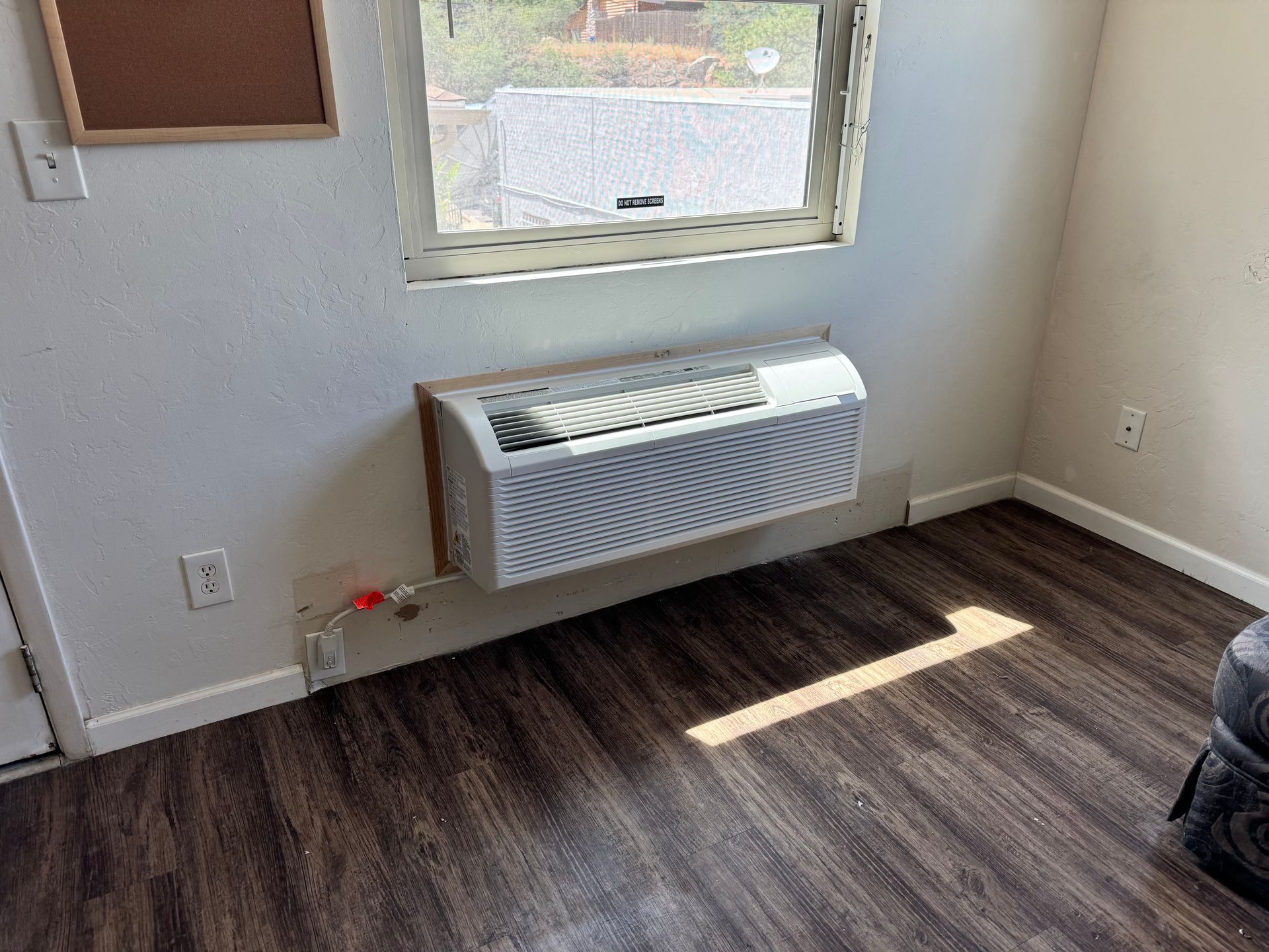 A room with a window and a wall mounted air conditioner.