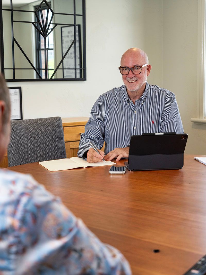 Man in striped shirt smiling at a conference table with a tablet and papers in a meeting room