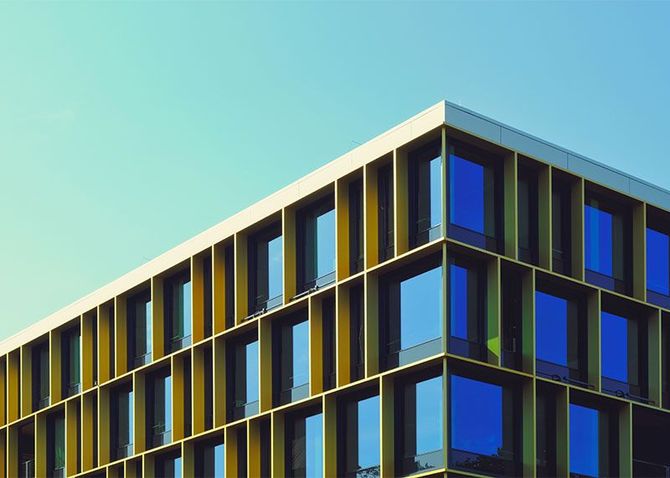 Modern office building with dark blue windows and yellow vertical accents against a clear sky