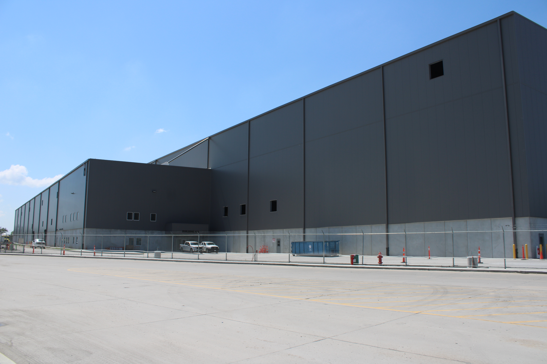 Gray Wieland warehouse building under a clear blue sky, with a few parked cars in front