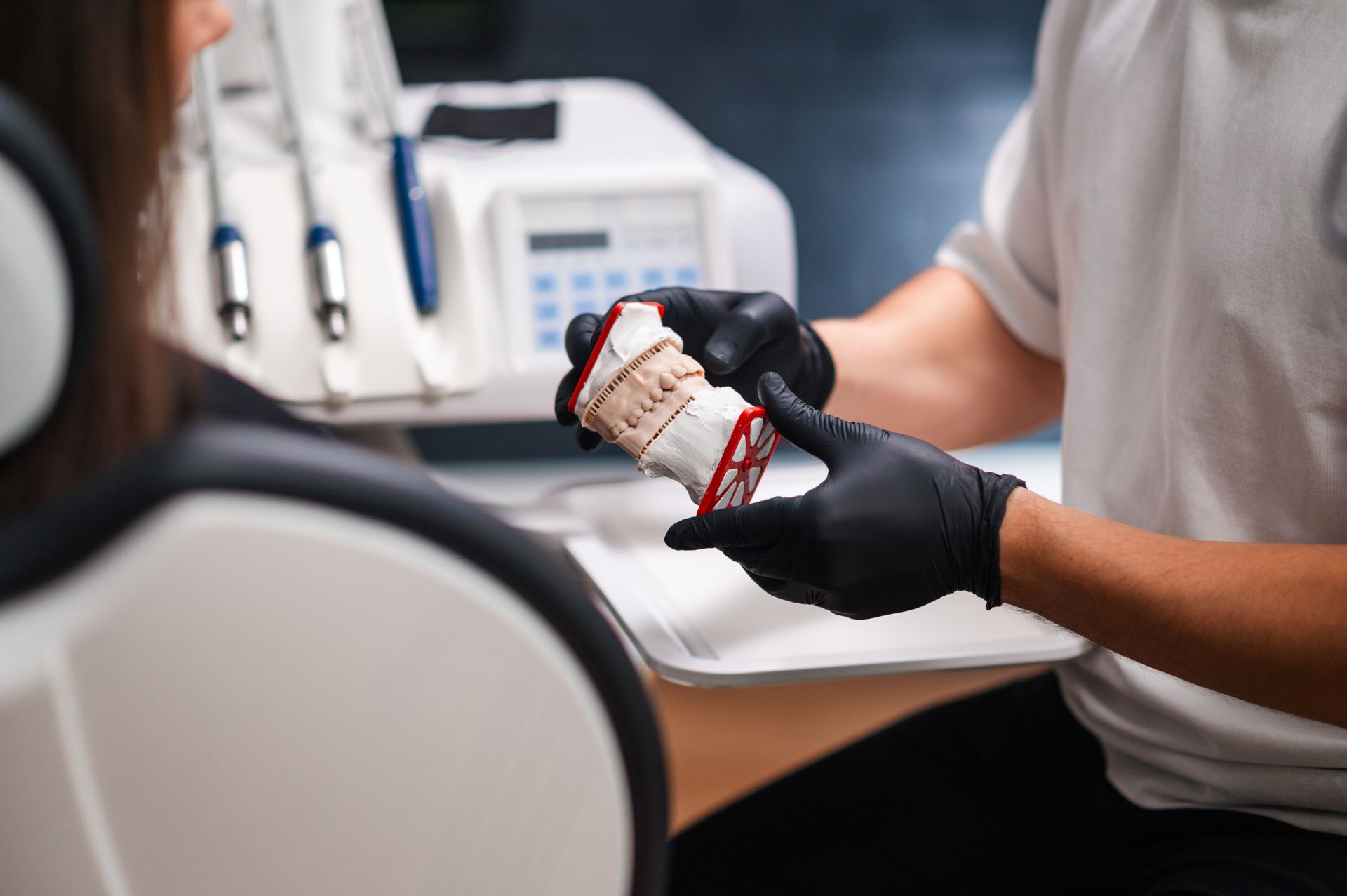 A dental professional holding a plaster cast model of a patient's teeth. A dental professional holding a plaster cast model of a patient's teeth.