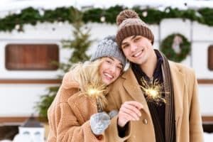 Couple holding sparklers for New Year celebration outside with bright smiles from teeth whitening.