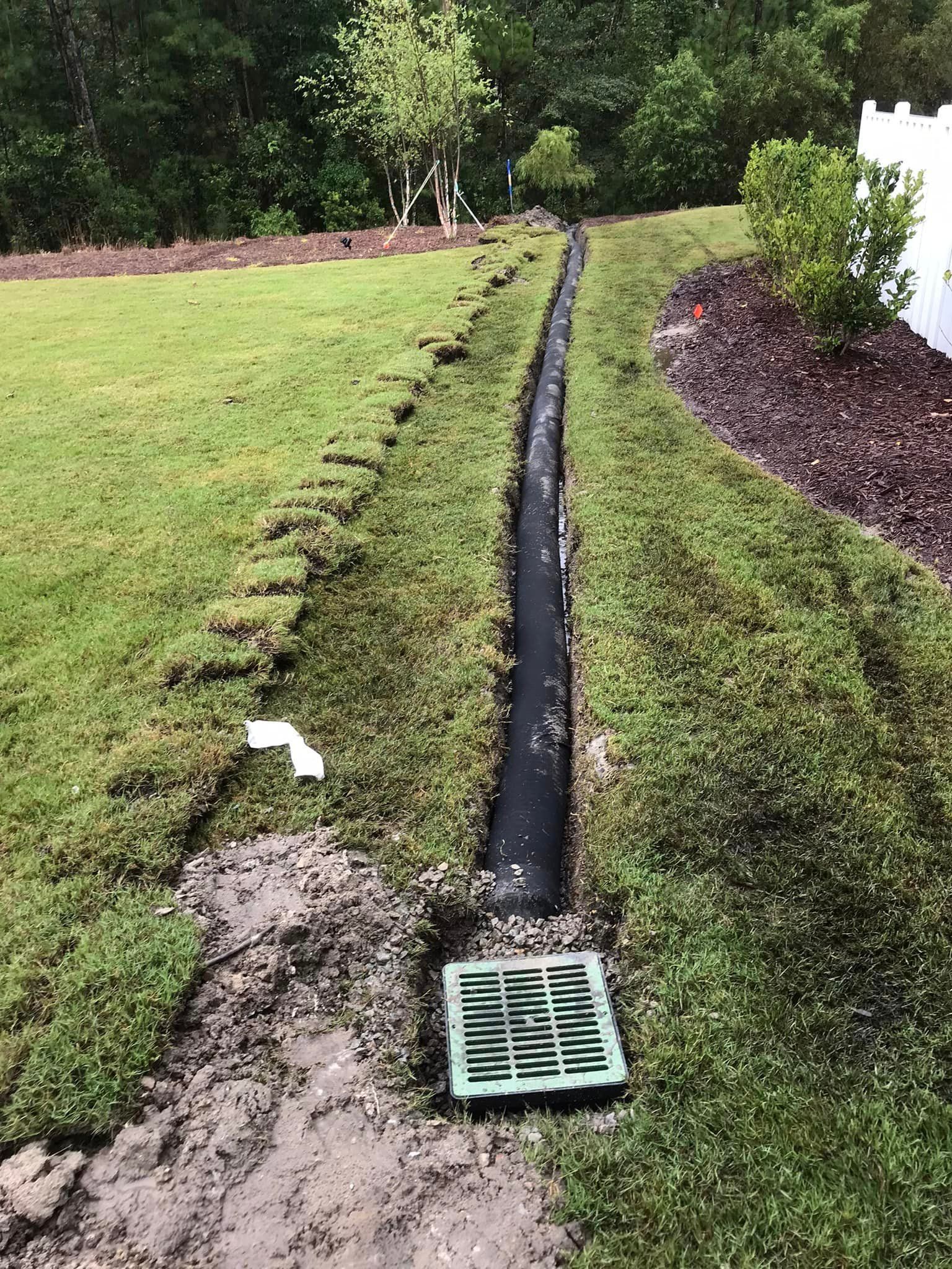 A drain is being installed in the middle of a lush green lawn.