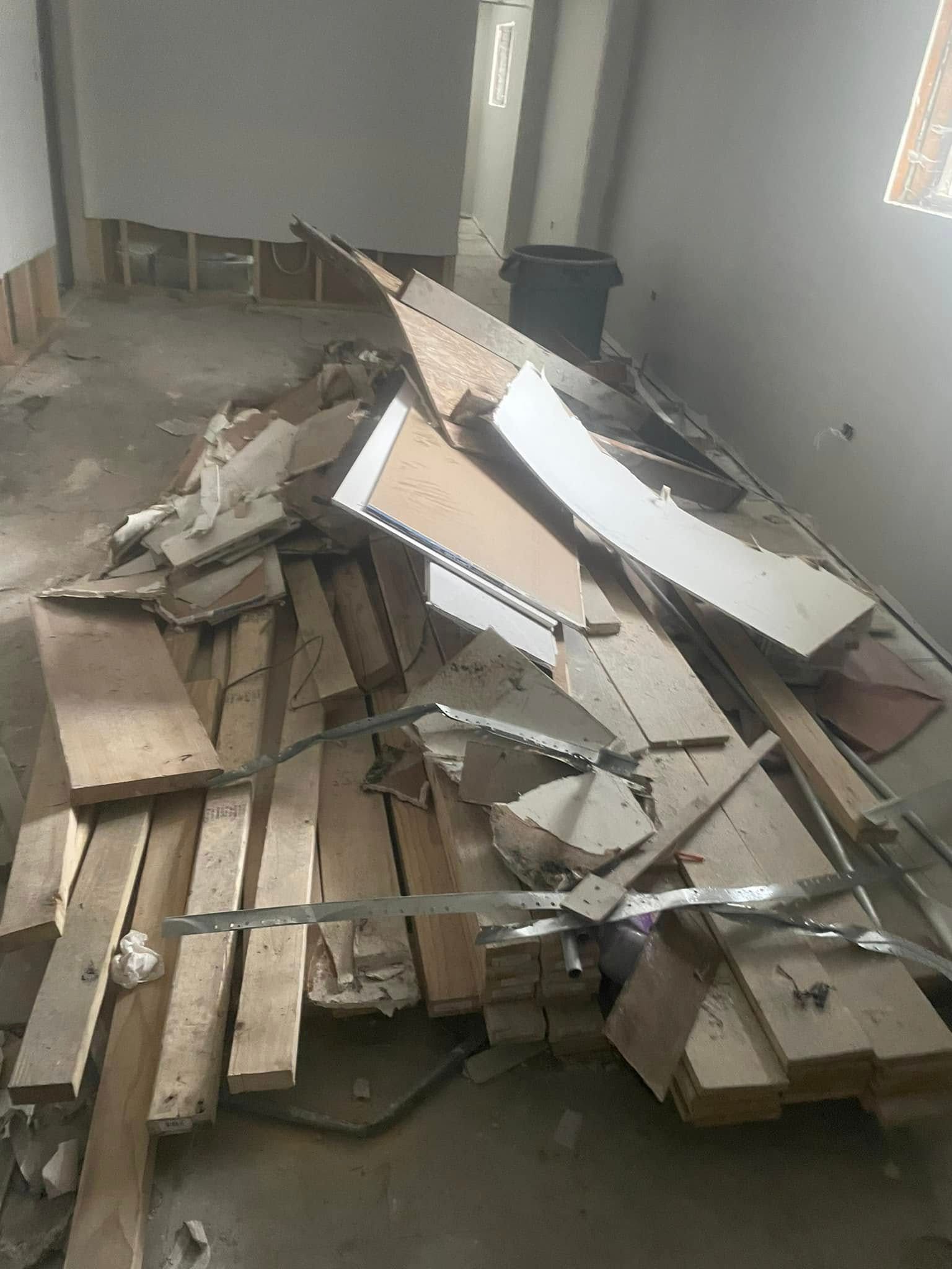 Piles of broken cardboard and wood debris scattered across an unfinished room floor.