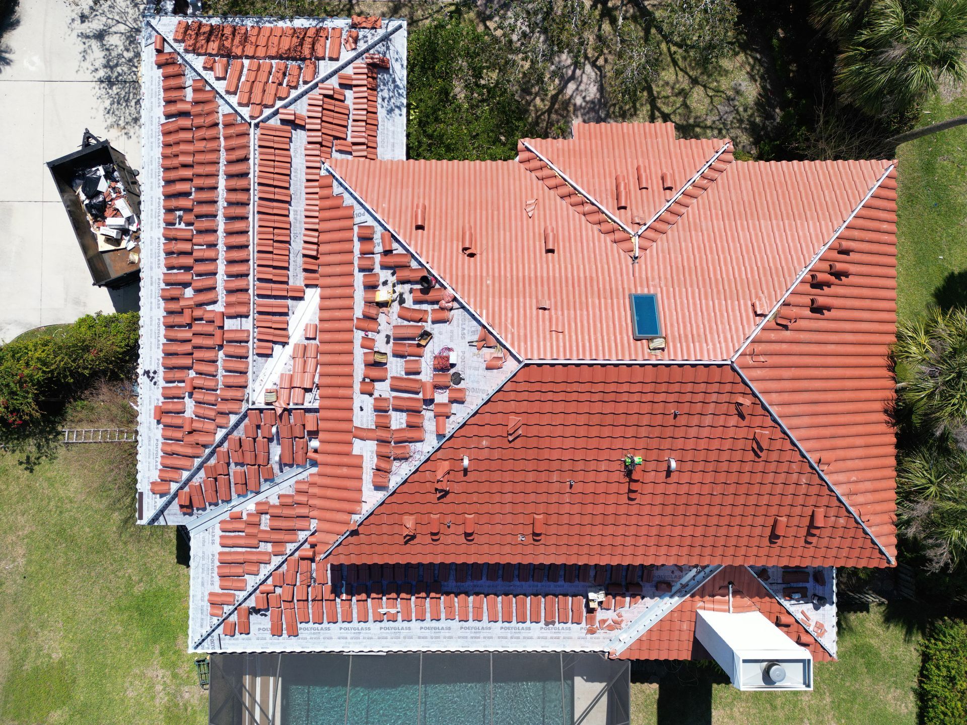 Tile underlayment replacement near you: Red Truck Roofing crew stacking lifted roof tiles and installing new self adhered underlayment before the re-lay
