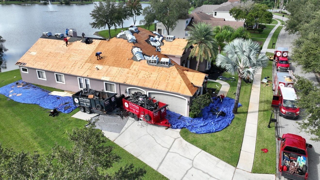 Emergency roof tarping near you: Red Truck Roofing crew fastening a tarp with furring strips over a hurricane opened roof at night in Tampa Bay