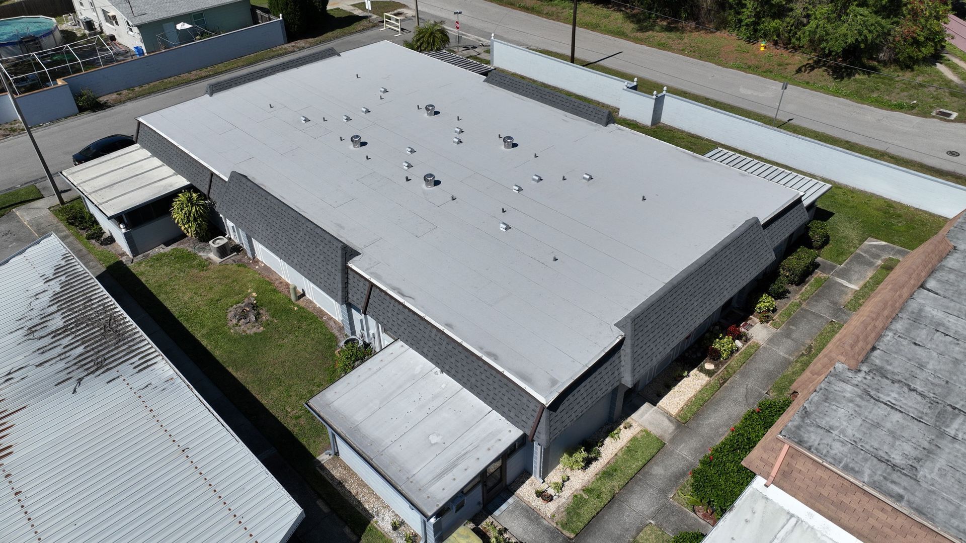 TPO roofing near you: Red Truck Roofing installer running a hot air welder along a TPO membrane seam on a Tampa Bay office building