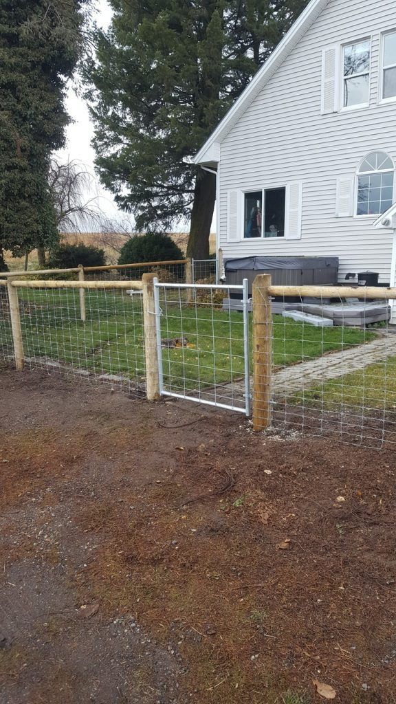 A wooden fence with a gate in front of a white house.