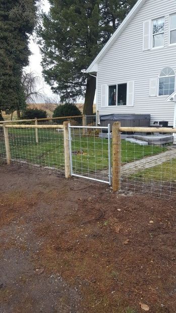 A wooden fence with a gate in front of a white house.