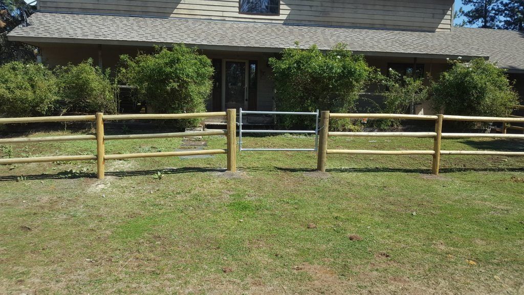 A wooden fence with a gate in front of a house.