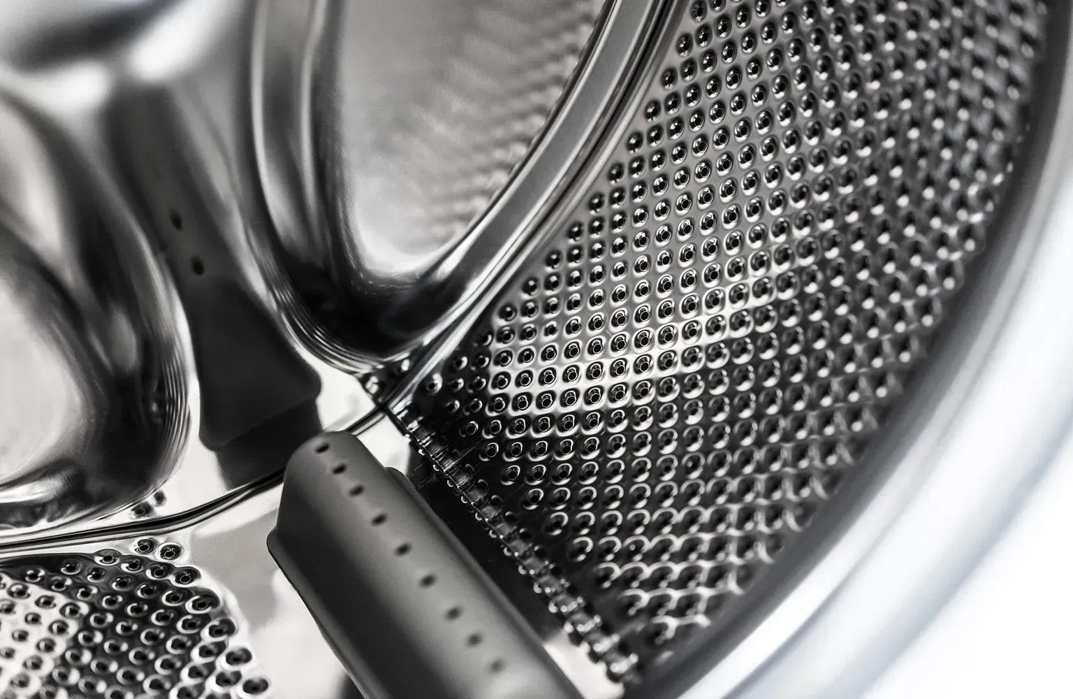 Close-up of a stainless steel washing machine drum interior with a dark gray component.