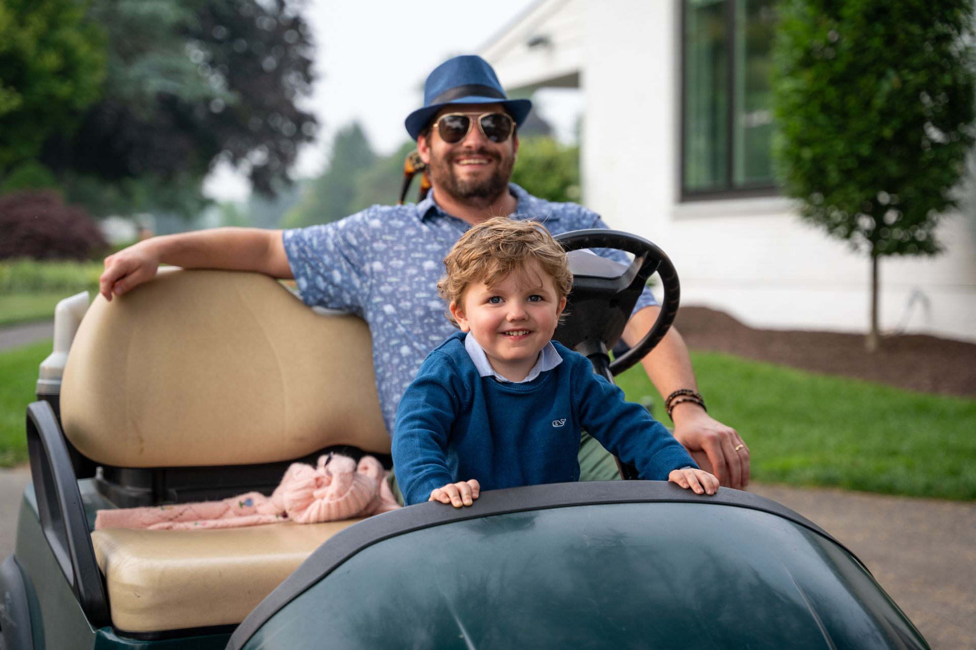 A man and a little boy are sitting in a golf cart.