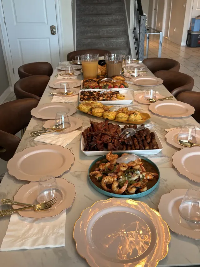 Long dining table set for a meal with multiple serving dishes in a bright home dining room