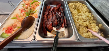 Three buffet trays with salad, glazed meat, and fried rice, with serving spoons.