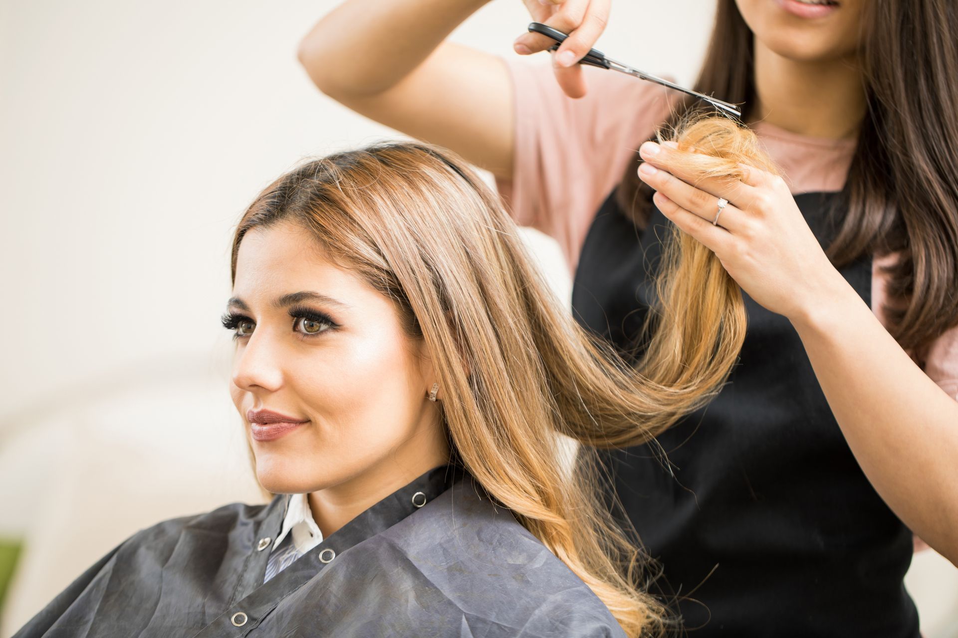 Stylist curling a woman’s hair in a salon chair