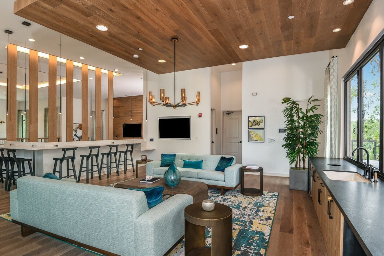 Open-concept lounge area with light blue sofas, bar seating, and a modern kitchen at Olympus Preserve at Town Center.