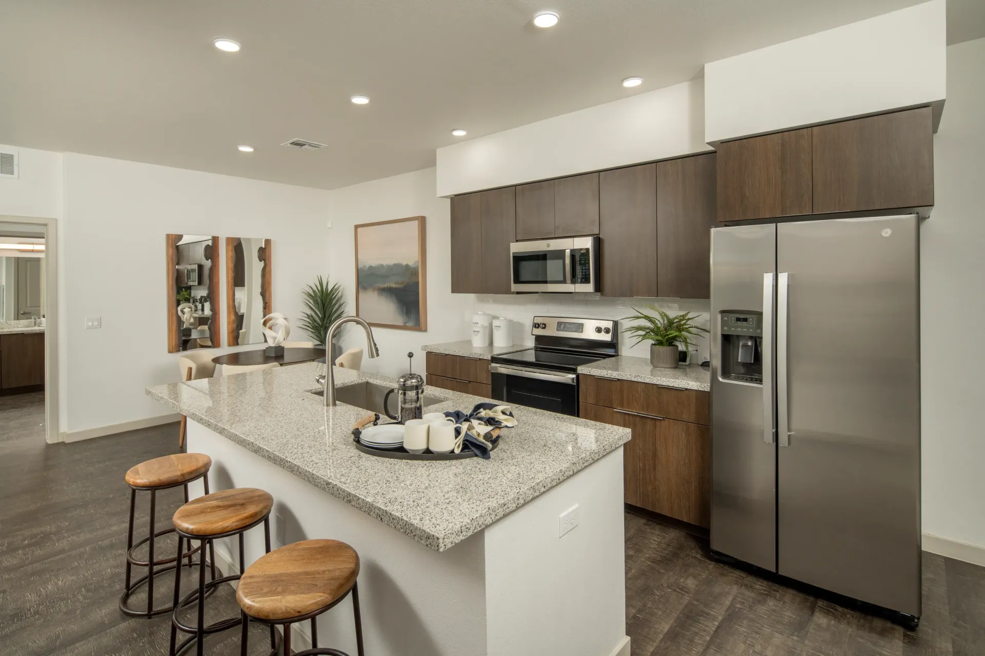 Modern kitchen with stainless steel appliances, granite countertops, and an island with bar stools at The Landing at Fiesta Village in mesa, AZ.