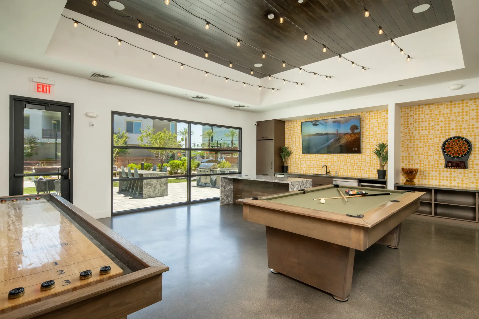 Community lounge with shuffleboard table, pool table, and dartboard at The Landing at Fiesta Village in mesa, AZ.