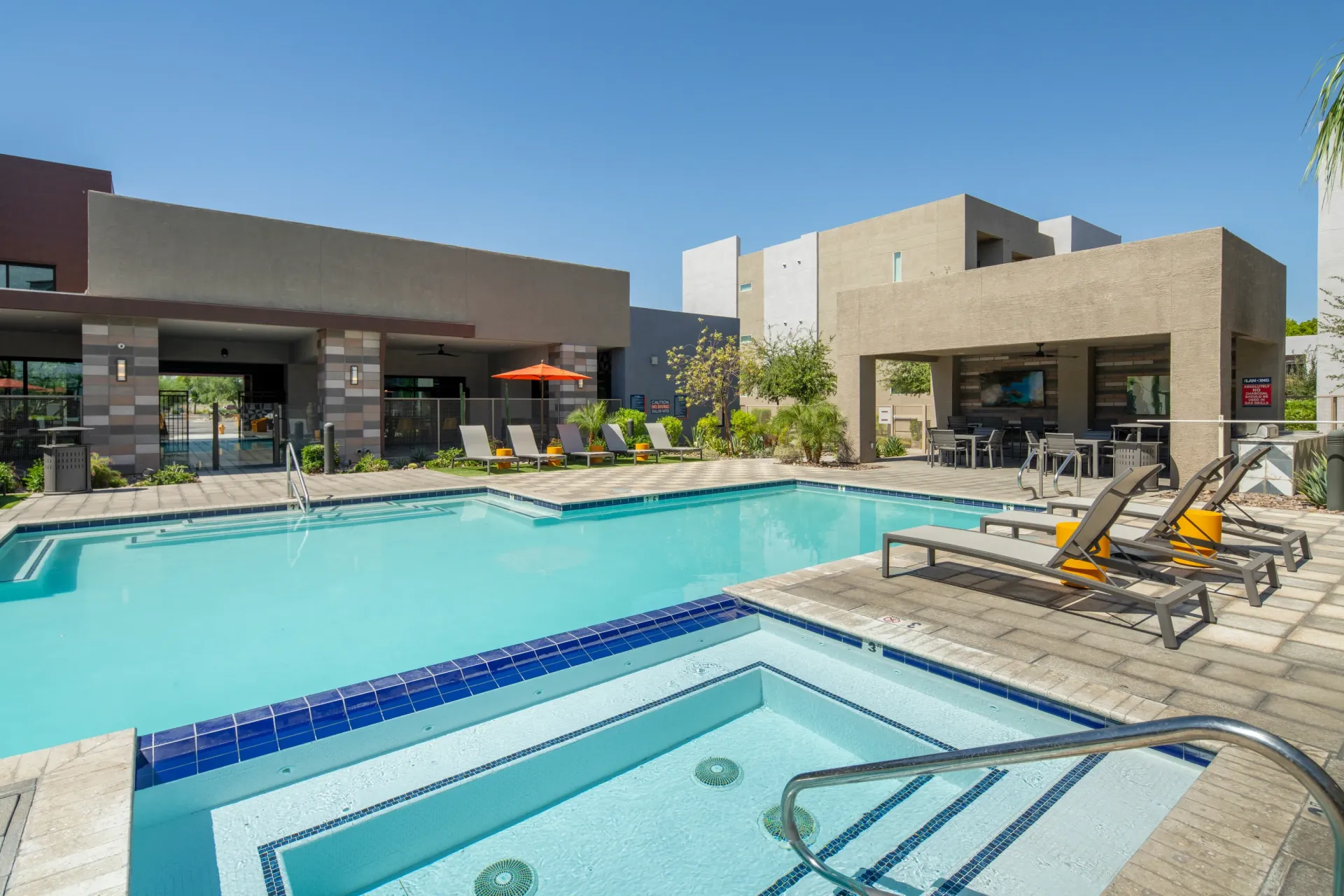 Outdoor swimming pool and hot tub area with lounge chairs and covered seating.