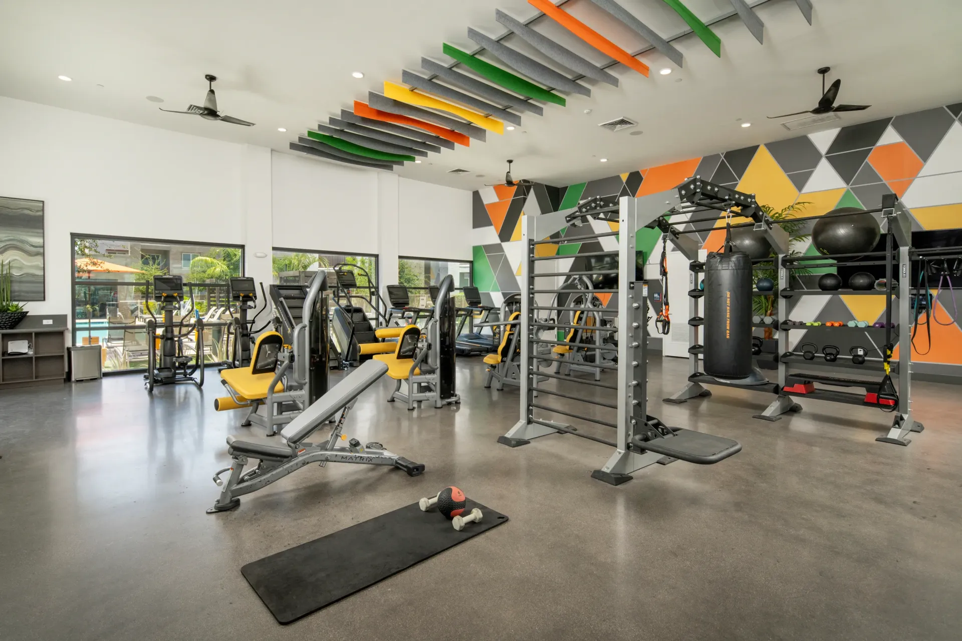 Modern gym with cardio machines, weightlifting equipment, and punching bag.
