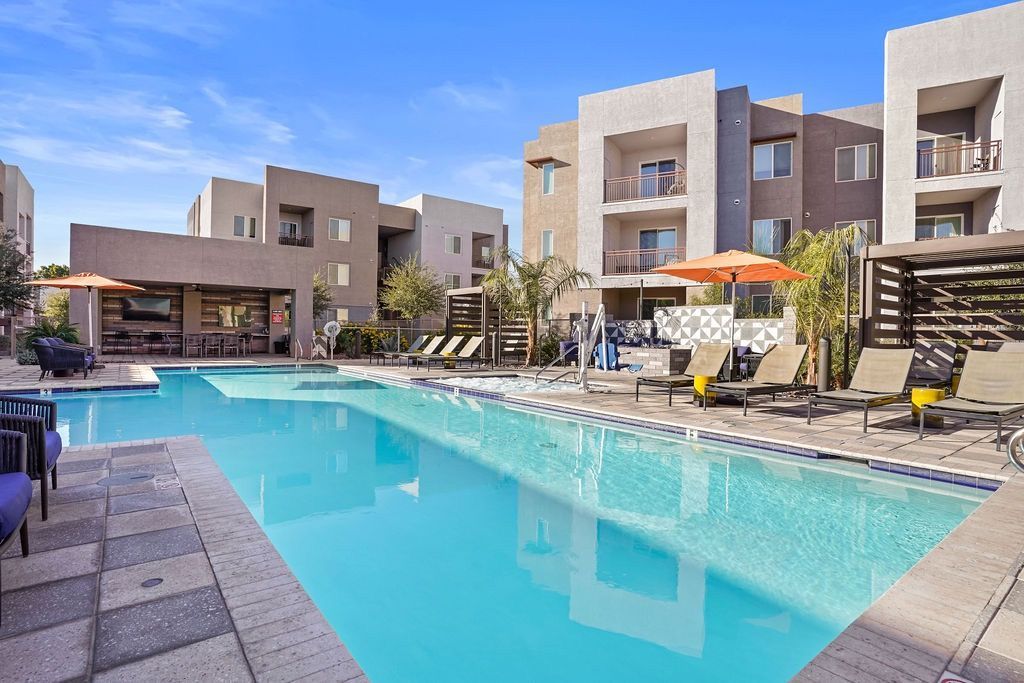 Outdoor pool in an apartment community with lounge chairs and umbrellas.