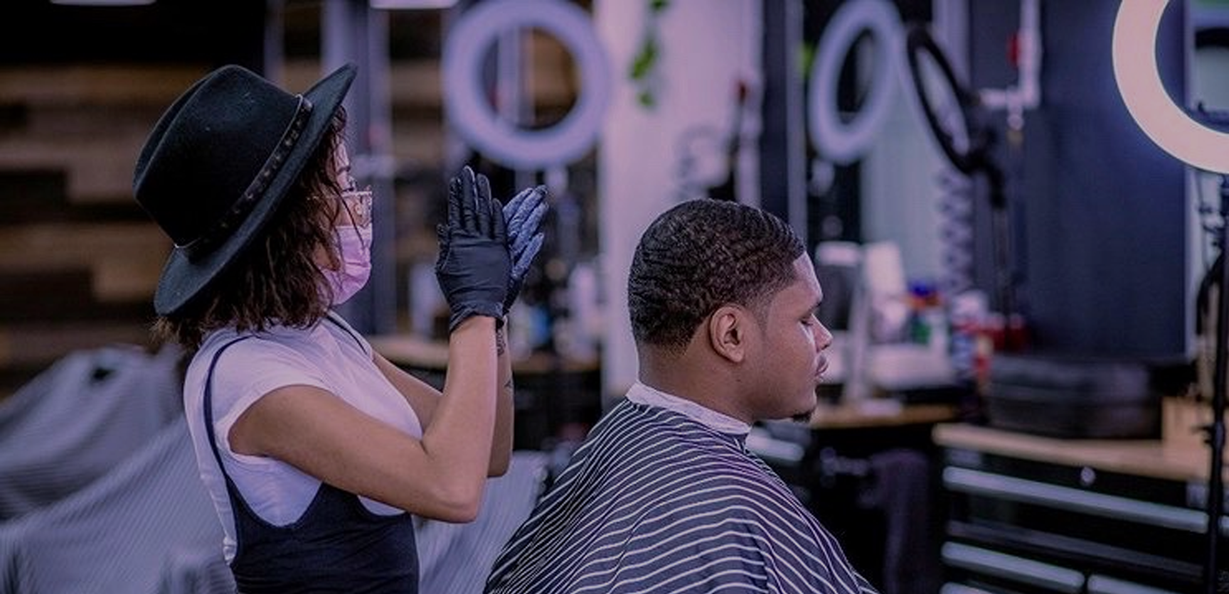 A woman is cutting a man 's hair in a barber shop.