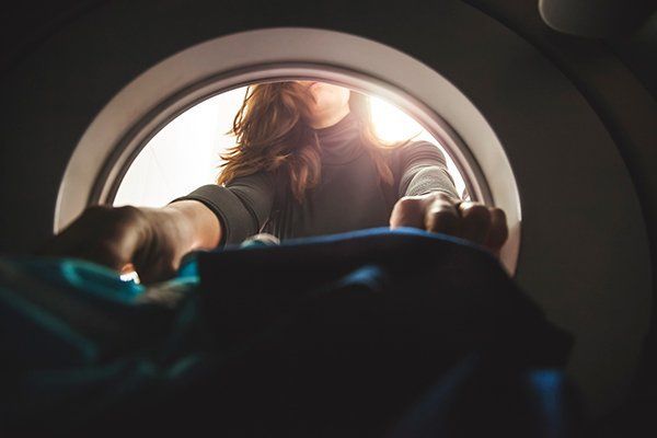 woman retrieving clothing out of washing machine