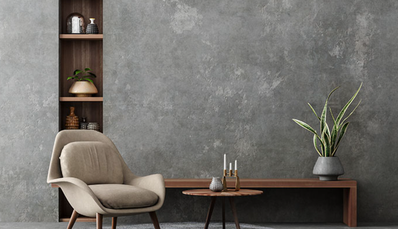 Minimalist living room with beige chair, wooden table, shelf, and large gray textured wall