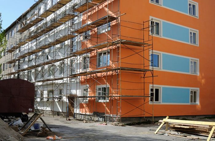 Orange apartment building under construction with scaffolding and blue windows