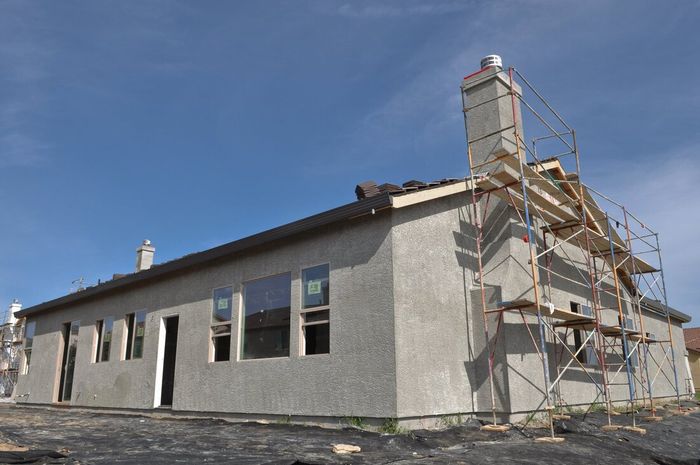 Single-story house under construction with scaffolding against a blue sky