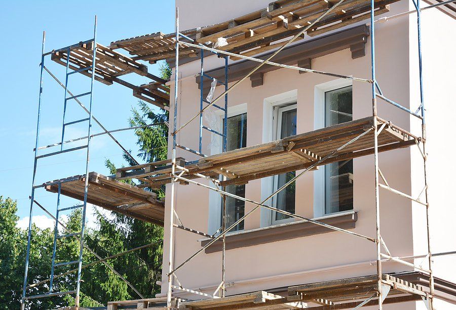 House under construction with scaffolding and wooden planks around the exterior.