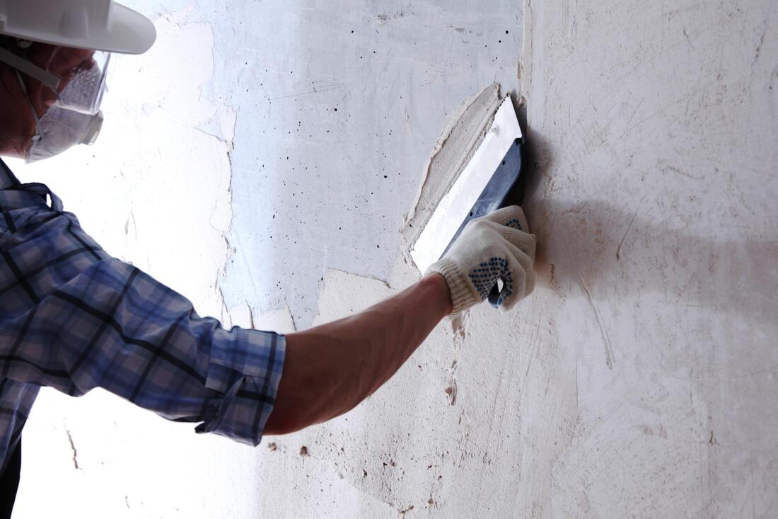 Worker plastering a white wall with a trowel