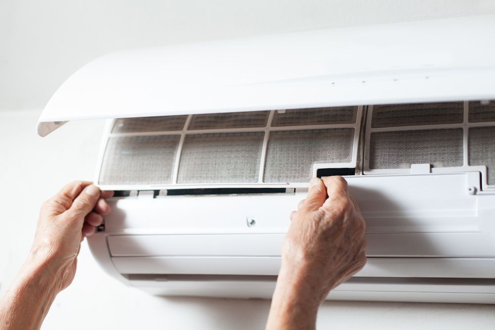 Hands Removing an Air Conditioner Filter for Cleaning — NTR Electrical In Toogoom, QLD
